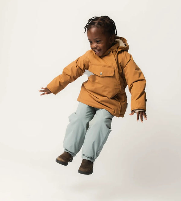 Child jumping in a chestnut Mini A Ture MATWANG fleece-lined winter jacket